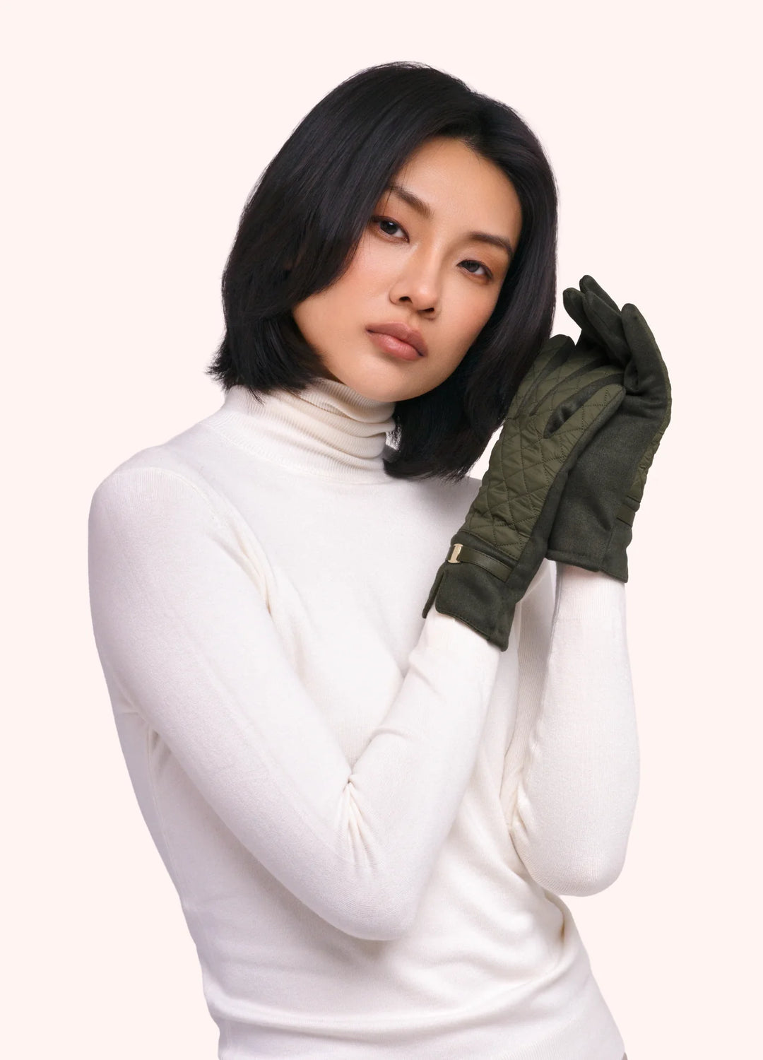 Woman wearing a white turtleneck and green gloves on a white background