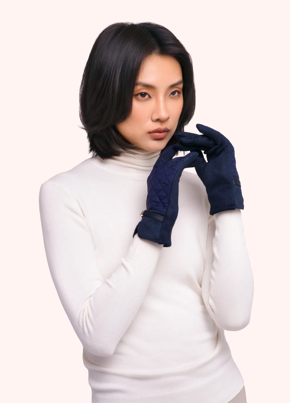 Woman wearing navy gloves against a white background