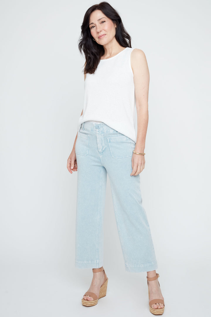 Woman wearing a white sleeveless top and light blue jeans on a white background