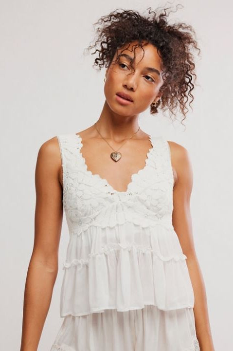 Woman wearing a white lace top and shorts set on a plain background