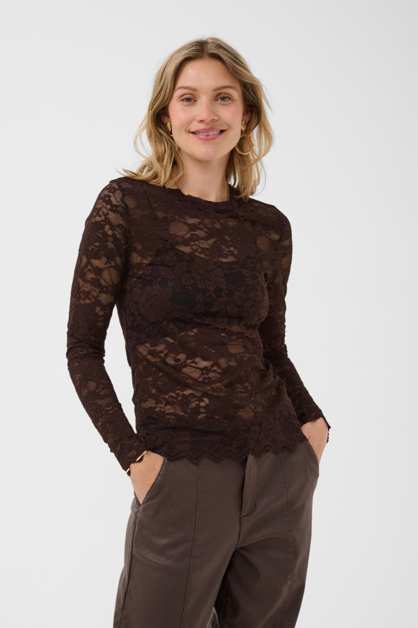 Woman wearing a brown lace top and gray pants on a white background