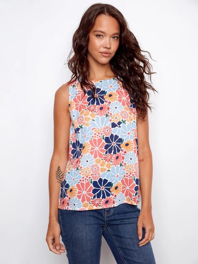 Woman wearing a sleeveless floral top with a white background