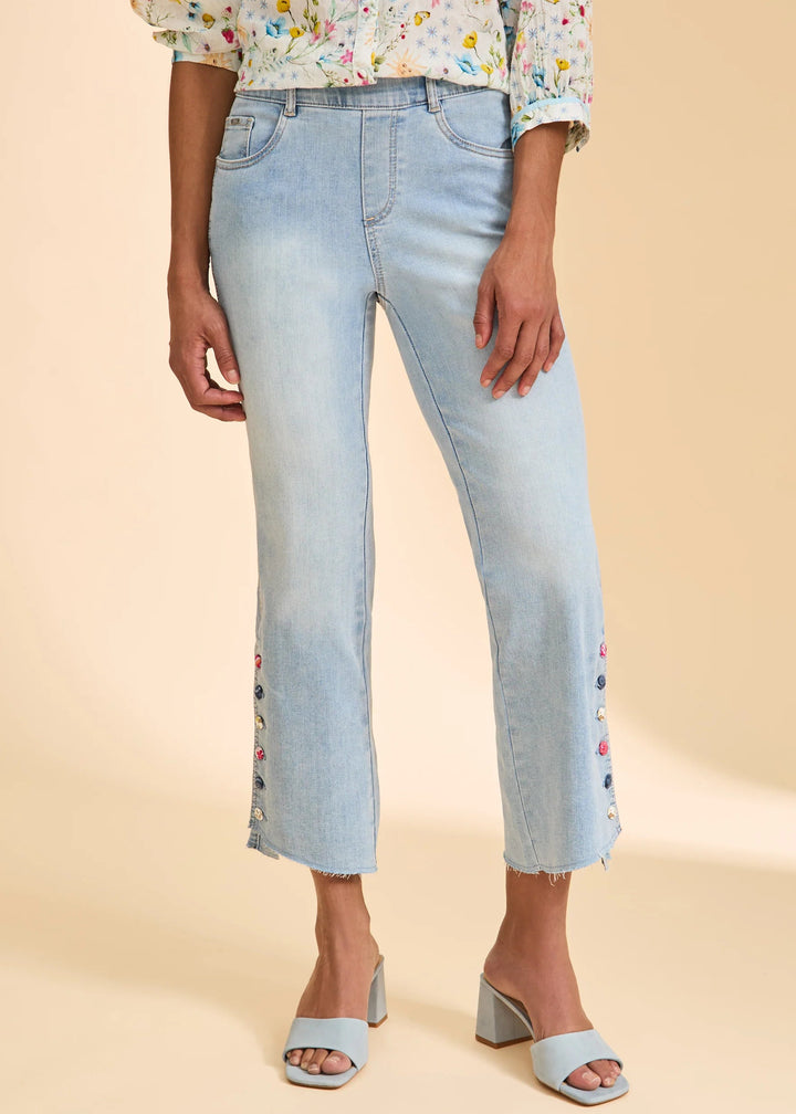 Person wearing light blue jeans with floral top on a beige background
