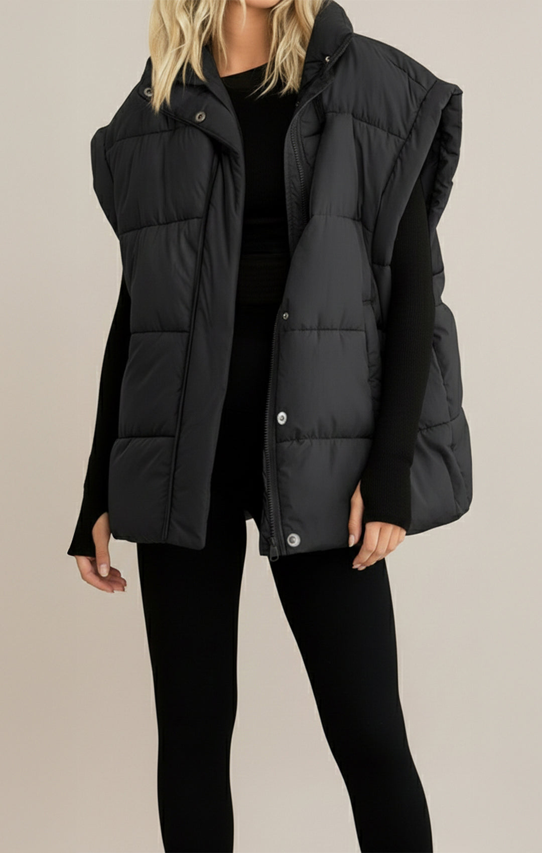 Person wearing a black puffer vest over a black outfit on a beige background