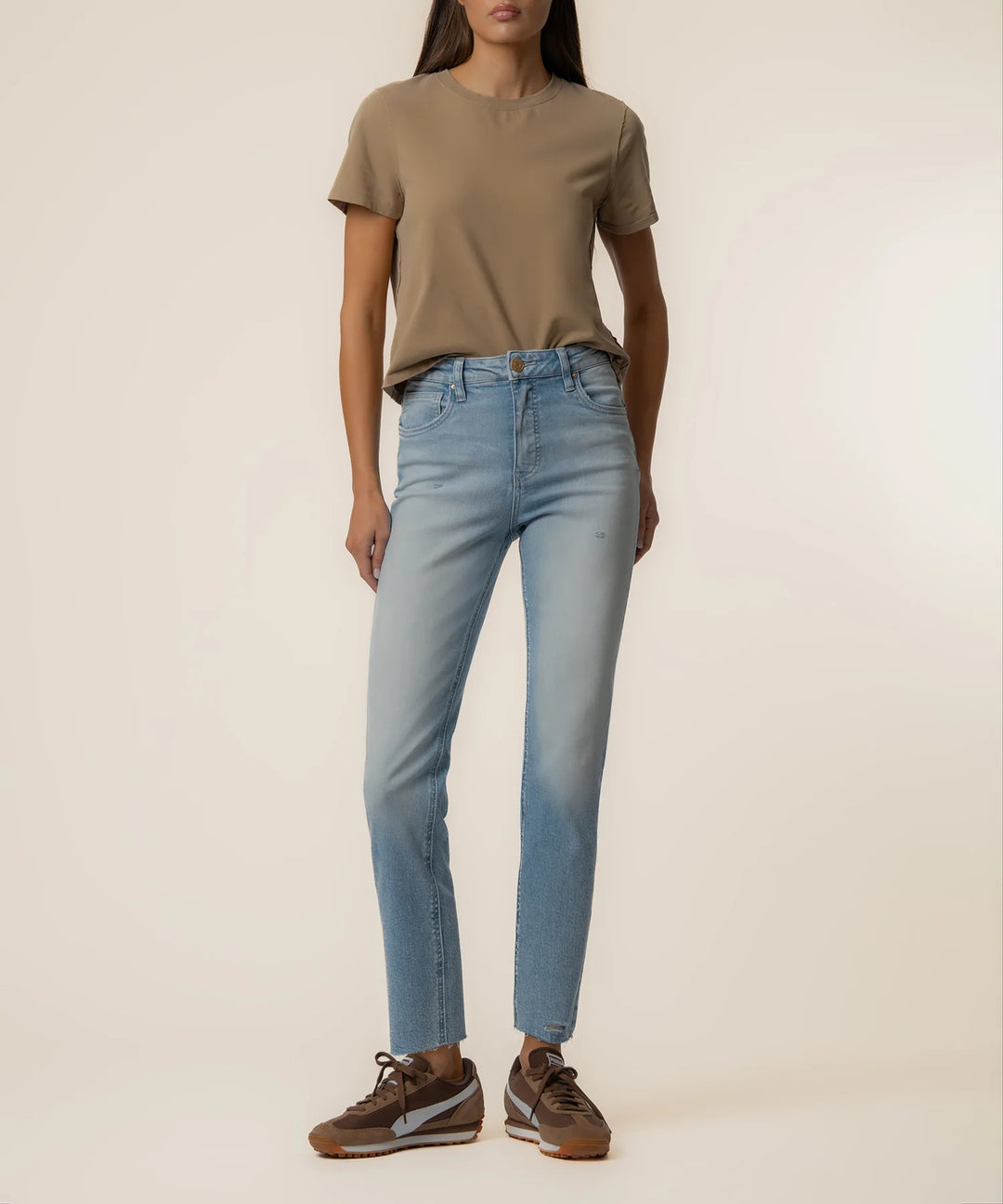 Person wearing a brown t-shirt and light blue jeans on a plain background