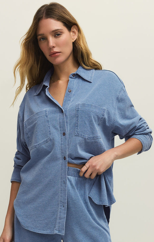 Woman wearing a blue denim shirt and pants on a plain background