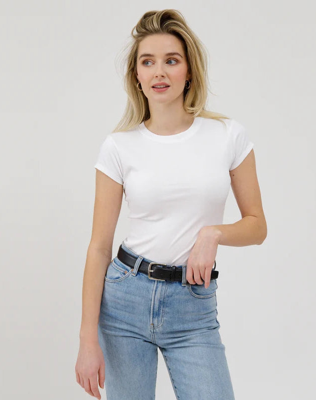 Woman wearing a white t-shirt and blue jeans against a plain background