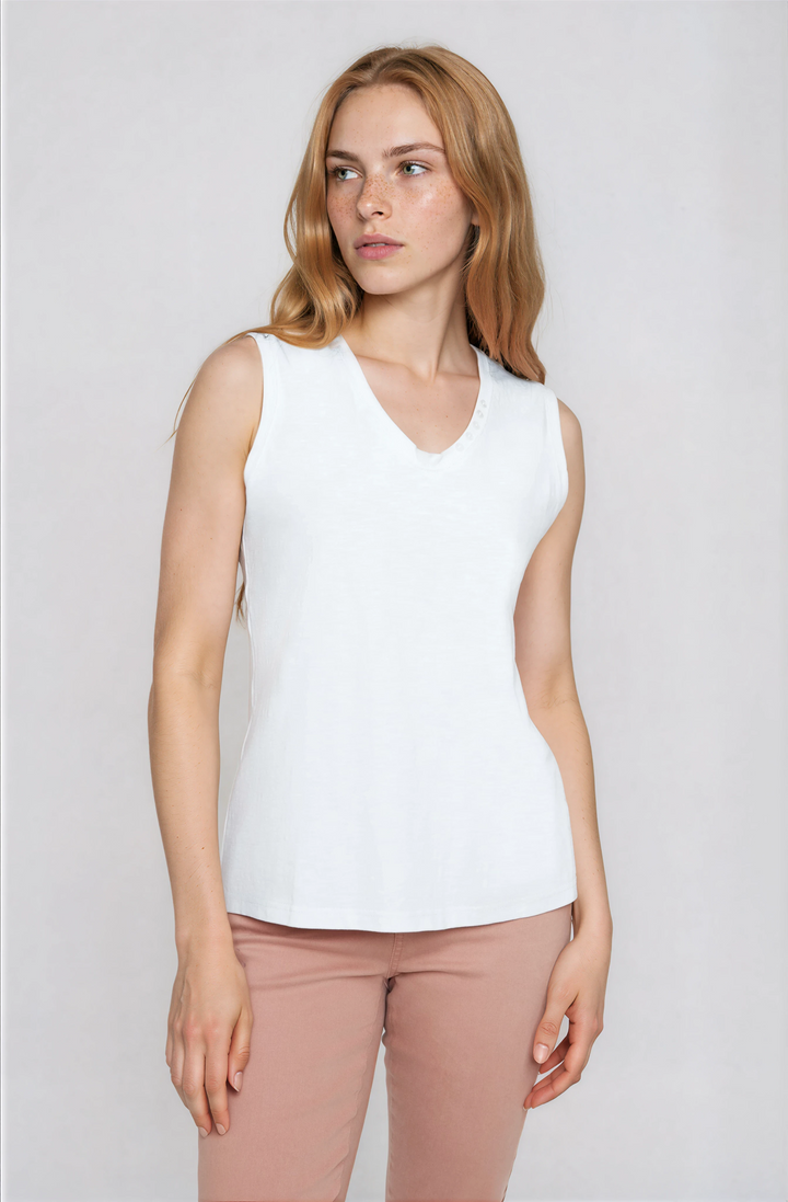 Woman wearing a white sleeveless top and pink pants on a plain background