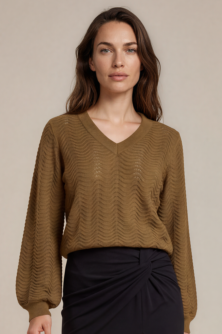 A woman modeling a brown textured knit long-sleeve sweater and a black high-waisted midi skirt with a front twist detail and thigh slit, paired with black flats, against a solid beige studio background.