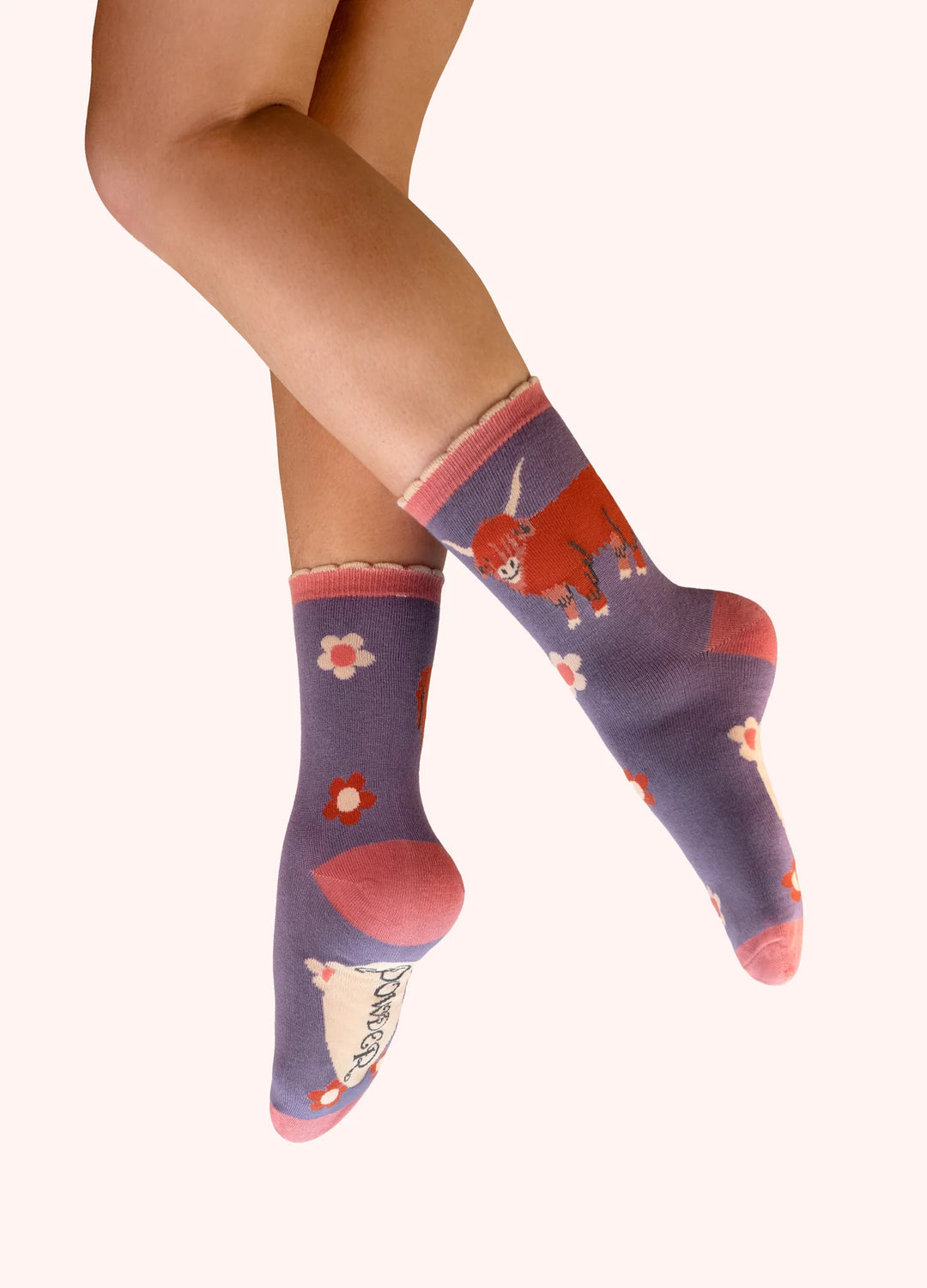 Purple socks with cartoon designs worn by a person on a white background
