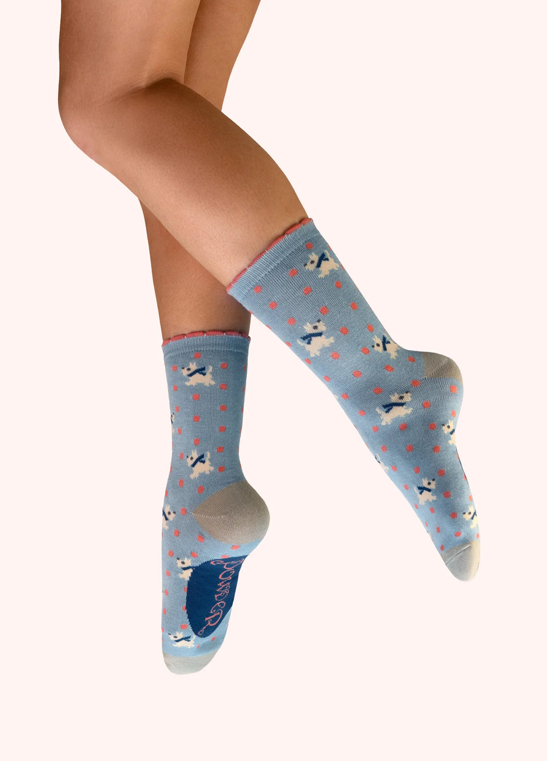 Light blue socks with dog pattern worn by a person on a white background