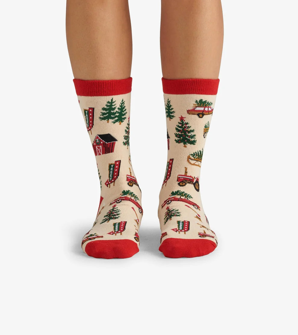 Socks with a festive design featuring trees, cabins, and trucks on a beige background.