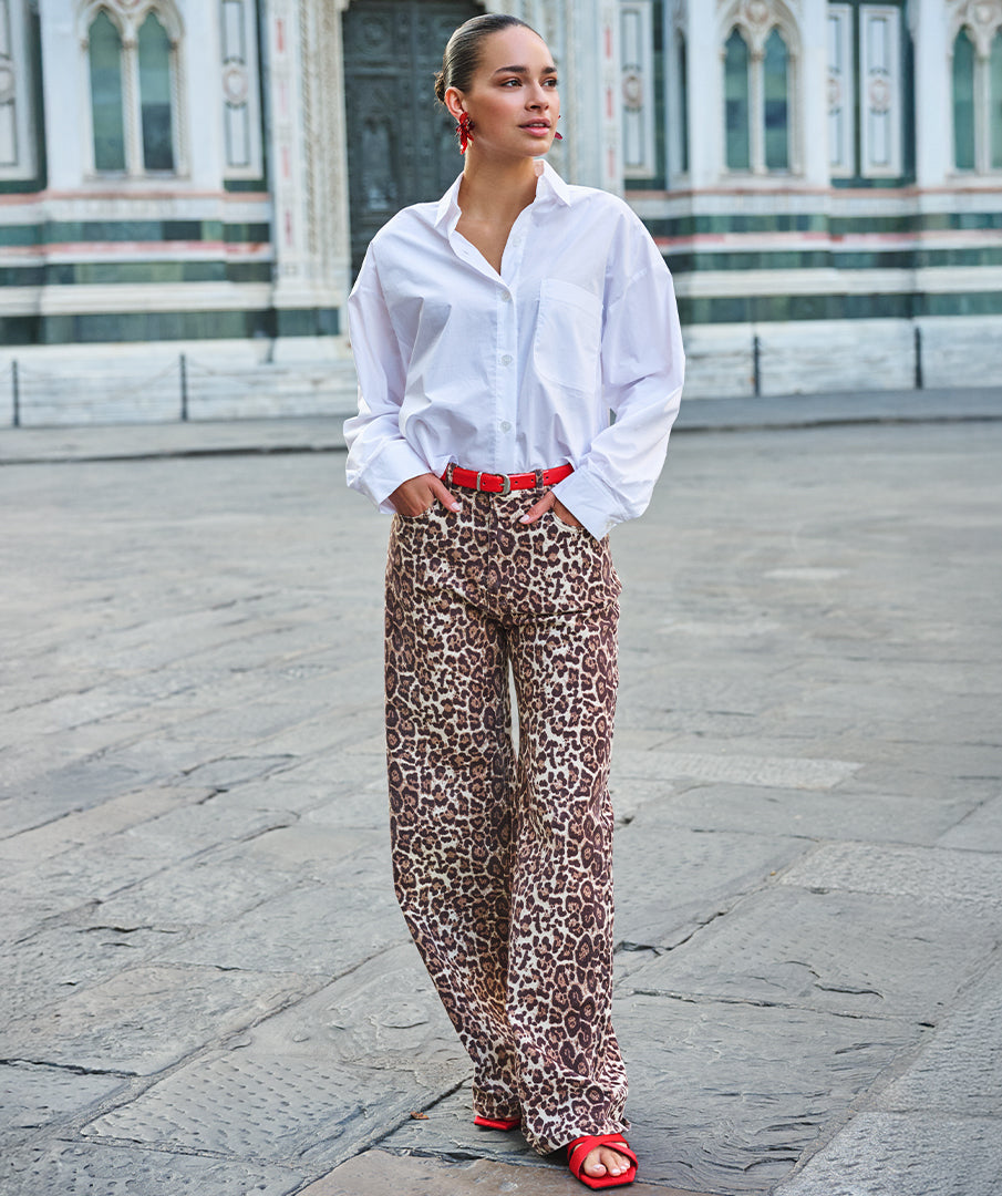 Person wearing a white shirt and leopard print pants in an urban setting