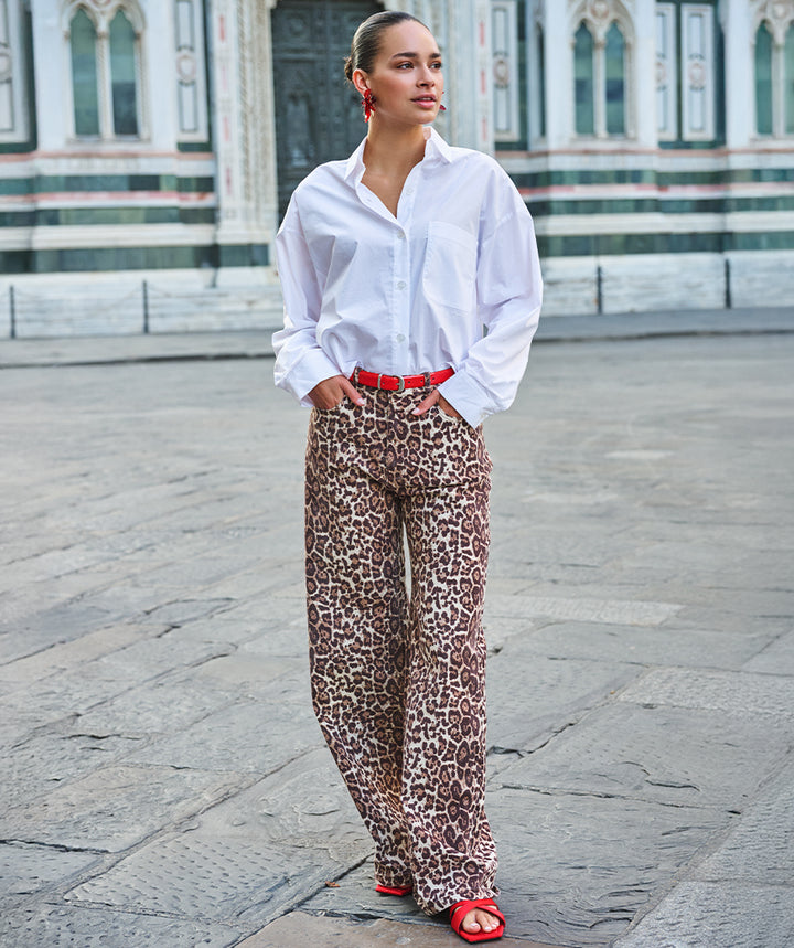 Person wearing a white shirt and leopard print pants in an urban setting