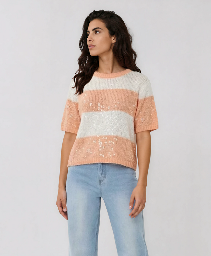 Woman wearing a striped sweater and jeans against a plain background