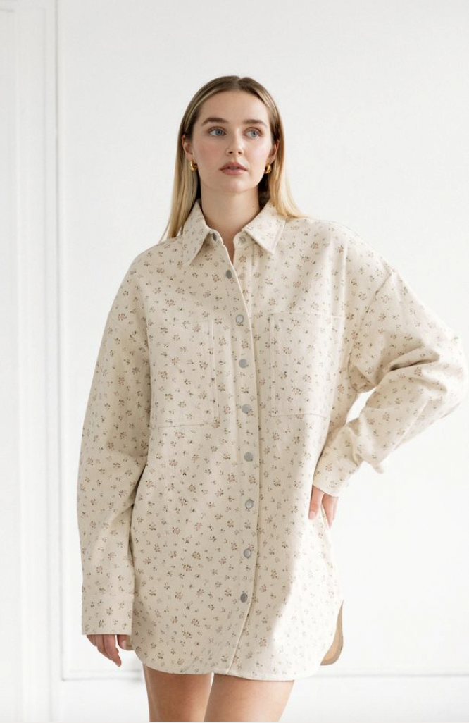 Woman wearing a beige patterned shirt dress against a white background