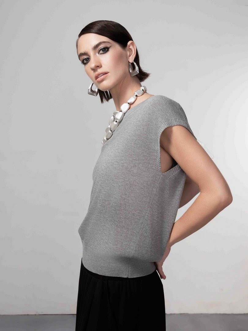 Woman wearing a gray top and black skirt against a plain background