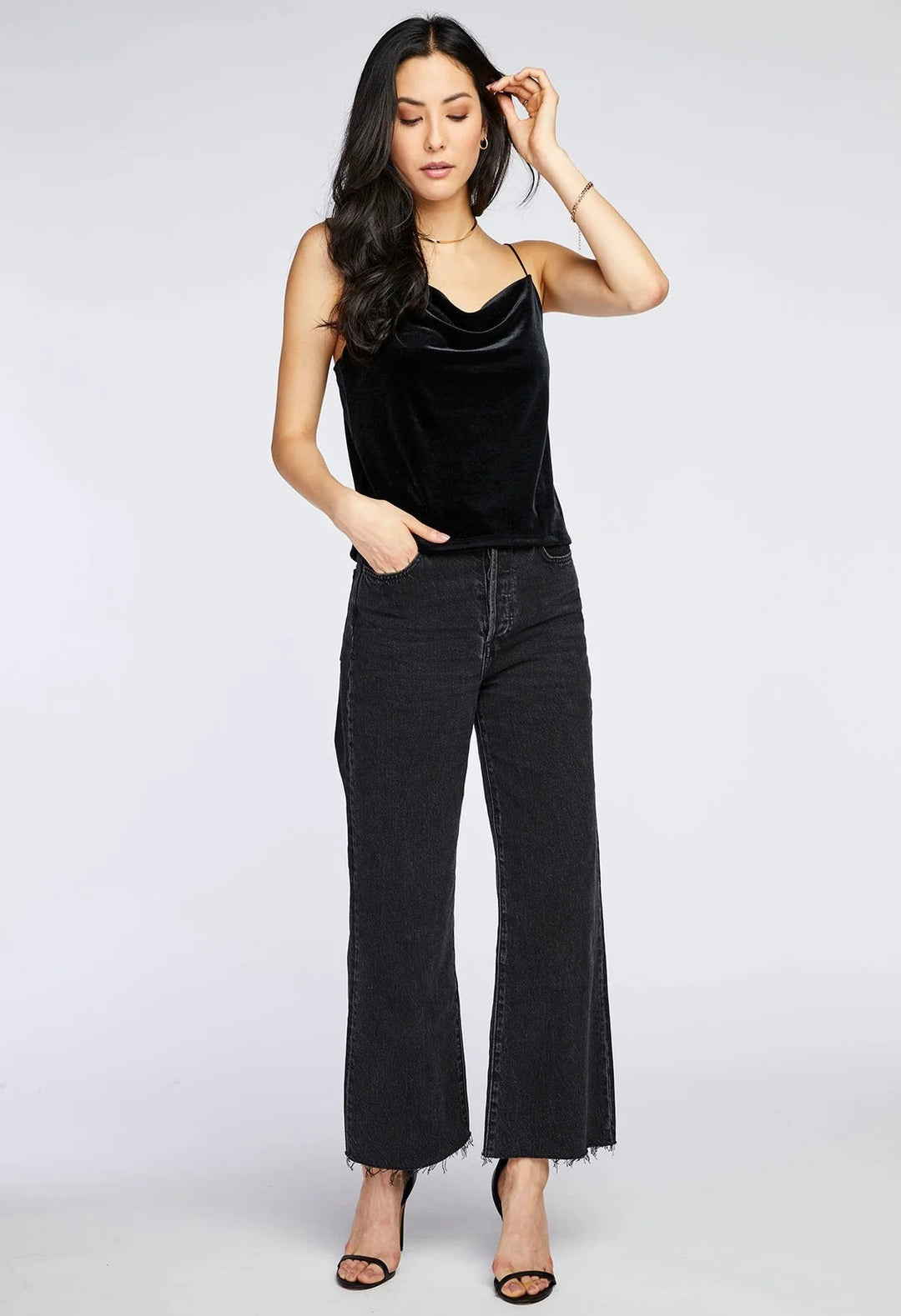 Woman wearing a black sleeveless top and black jeans on a white background
