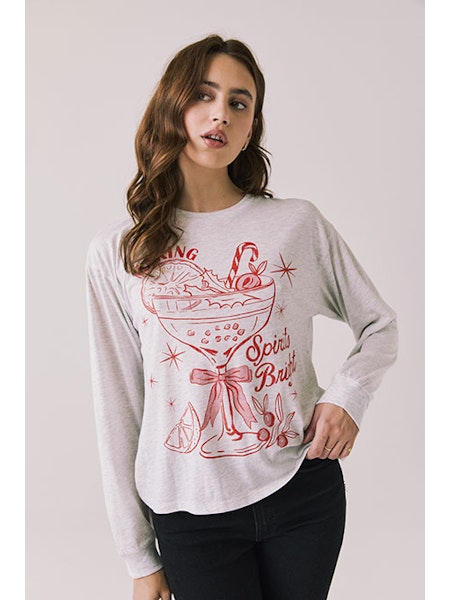 Woman wearing a white sweatshirt with red graphic design on a plain background