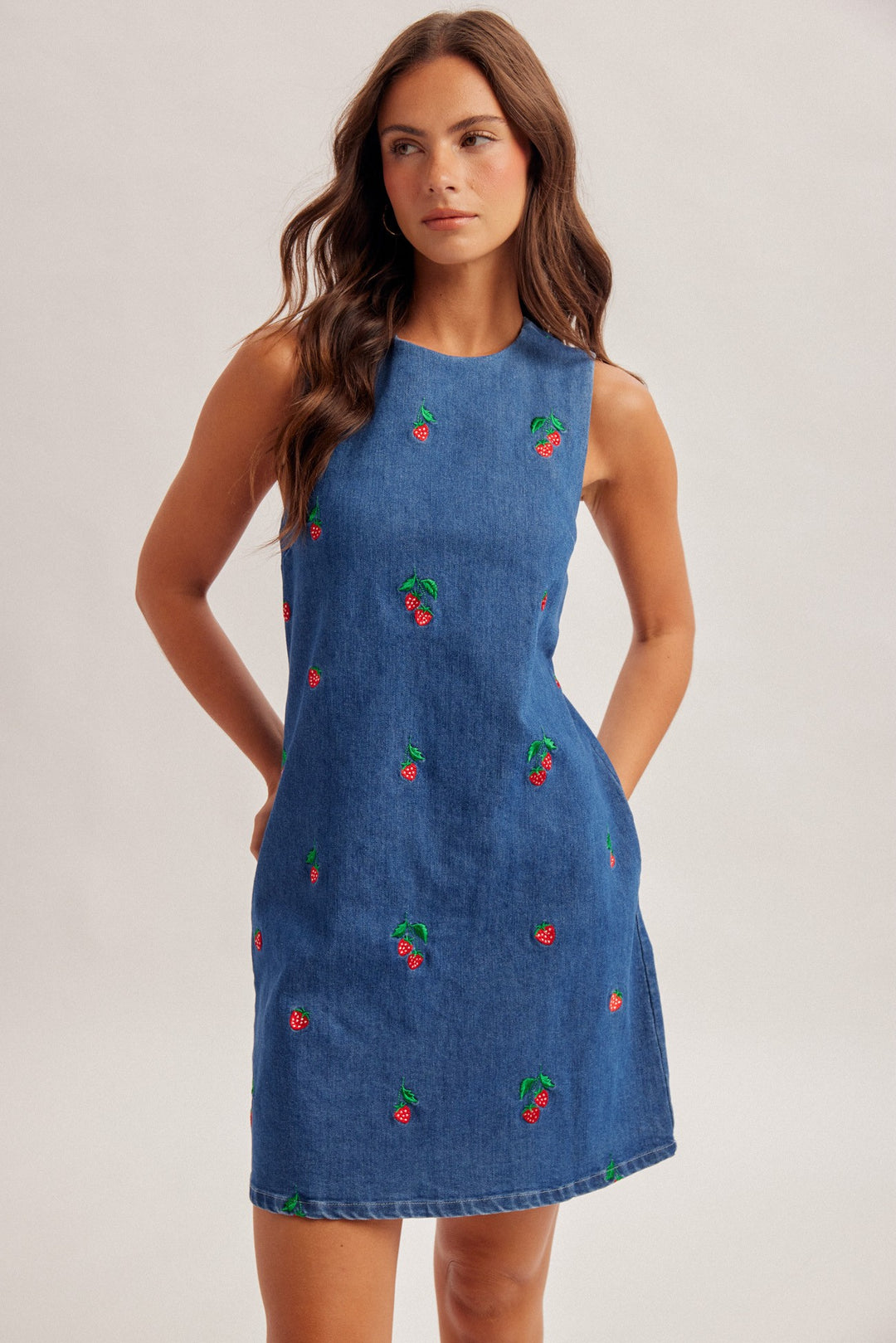 Woman wearing a blue dress with cherry patterns on a plain background