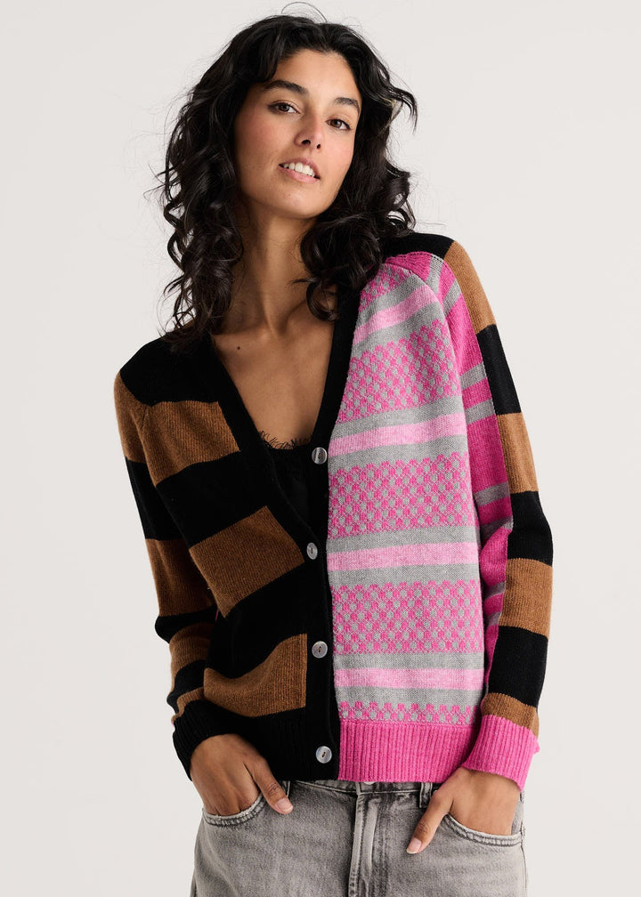 A woman modeling a color-block knit cardigan with pink, brown, black, and gray stripes, paired with light gray jeans, against a plain light gray background.