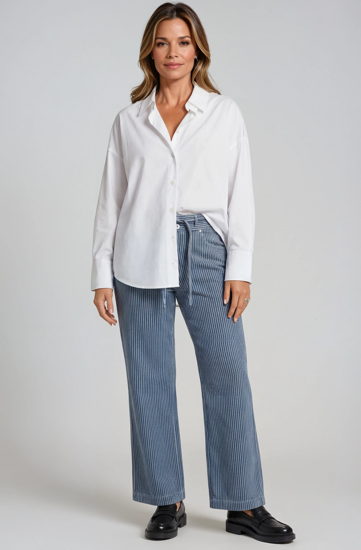 Woman wearing a white shirt and blue striped pants on a gray background