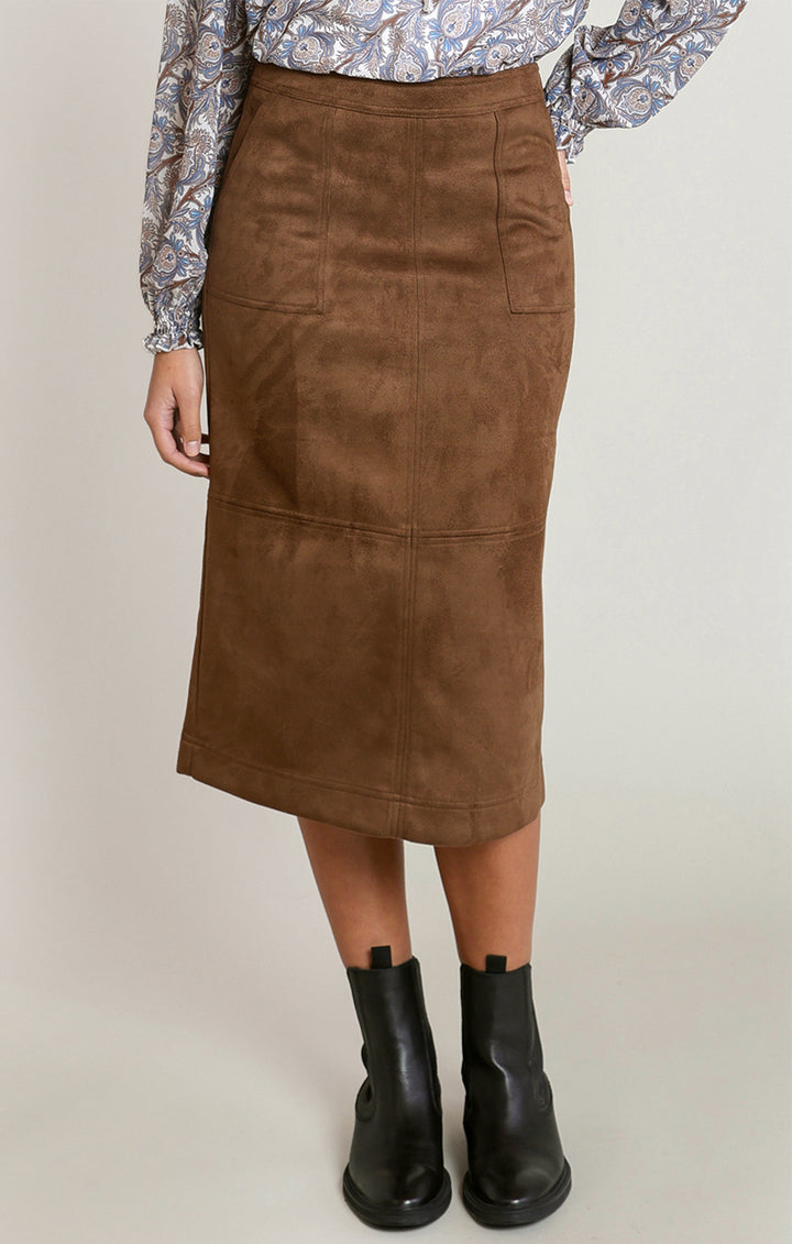 A brown midi skirt in a suede-like material, styled with a paisley blouse and black ankle boots, shown on a model against a light gray studio background.
