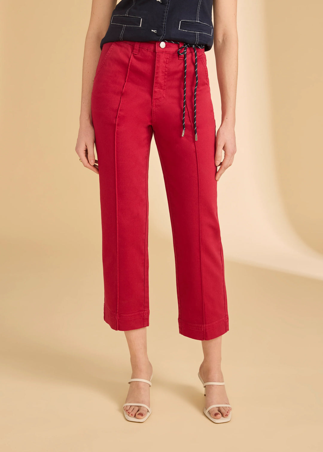 Red pants with a lace-up detail worn by a person on a beige background