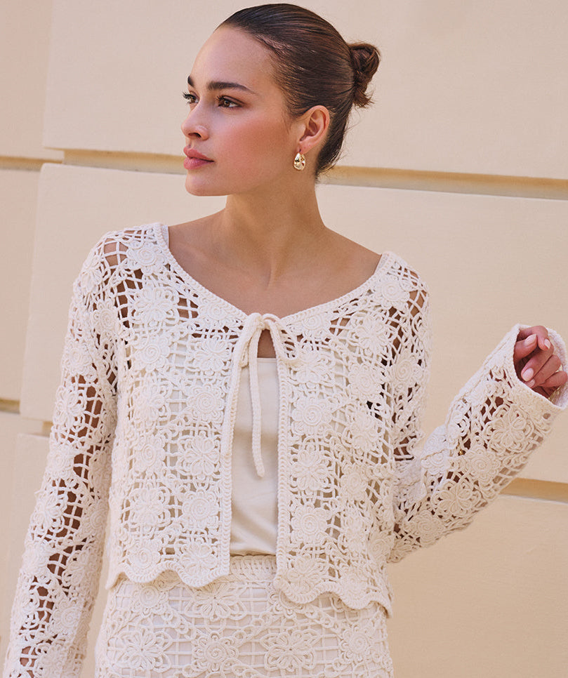 Woman wearing a white lace outfit against a neutral background
