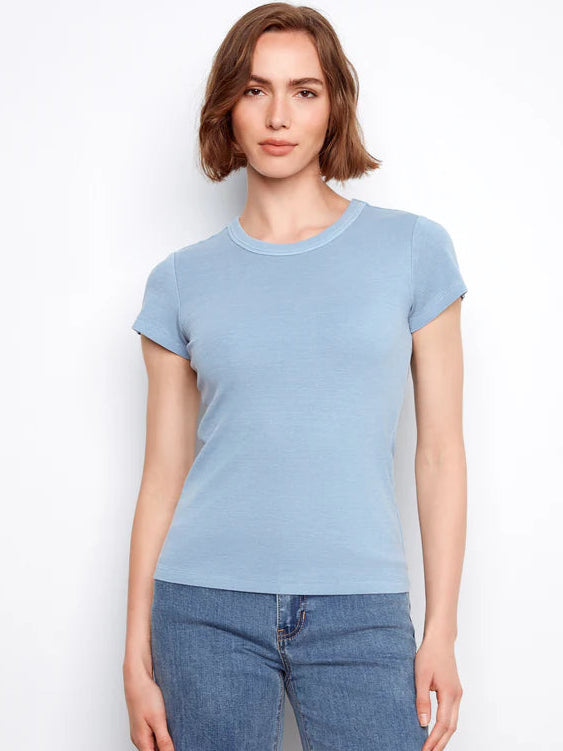 Woman wearing a light blue t-shirt and jeans against a white background