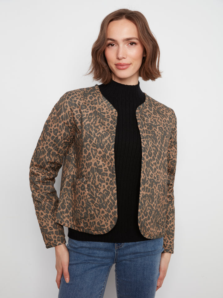 A woman modeling a cropped leopard-print jacket with a black ribbed turtleneck and blue jeans, shot against a plain light gray studio background.