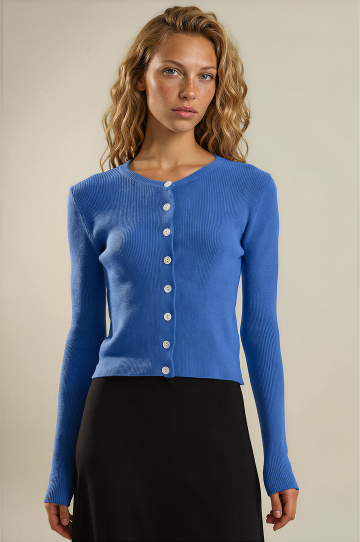 A woman modeling a bright blue long-sleeve knit cardigan with a button-front closure, paired with a black skirt, against a plain beige studio background.