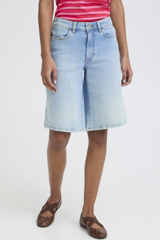 Person wearing a light blue denim skirt on a white background