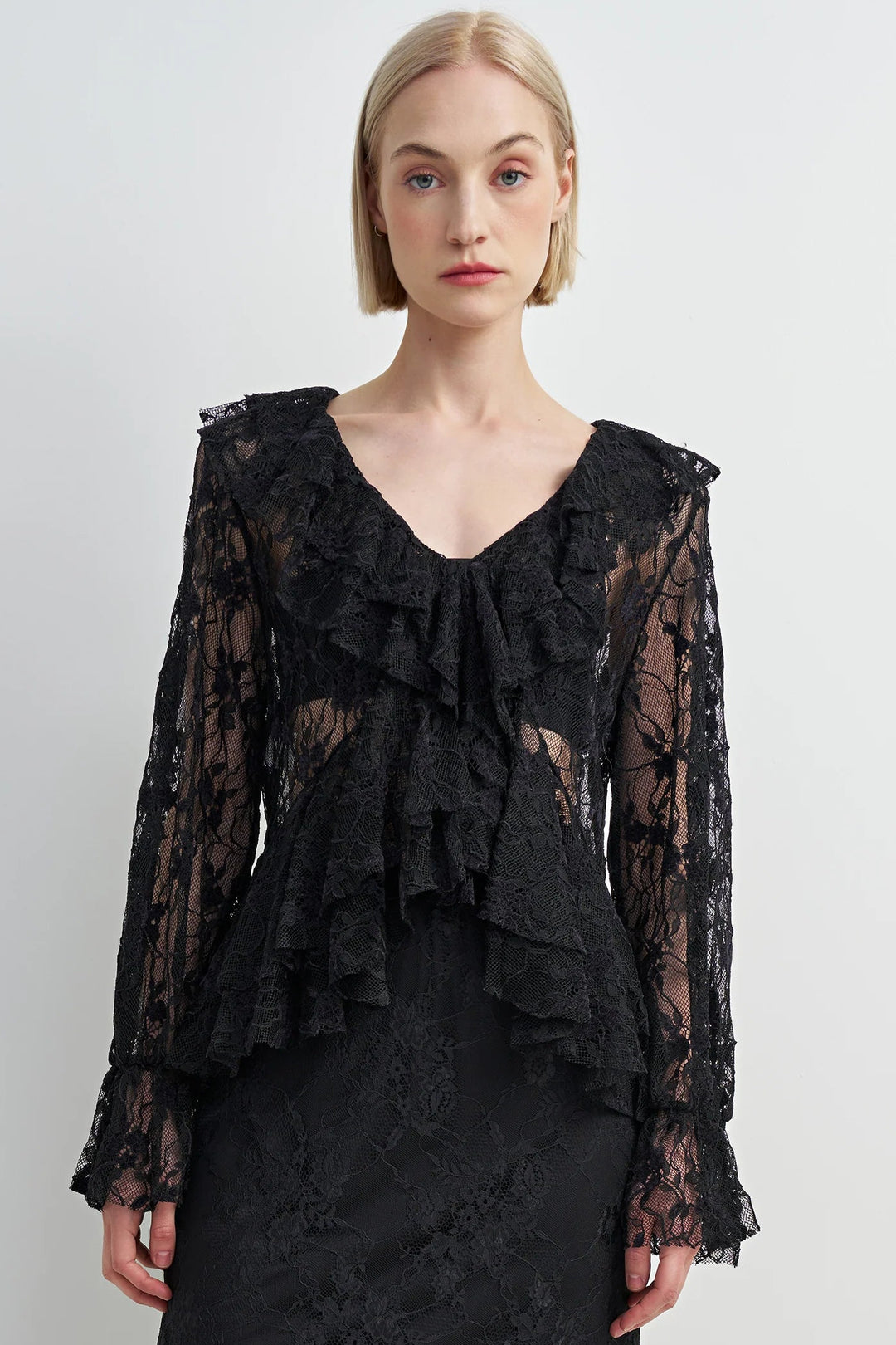 Woman wearing a black lace dress against a white background