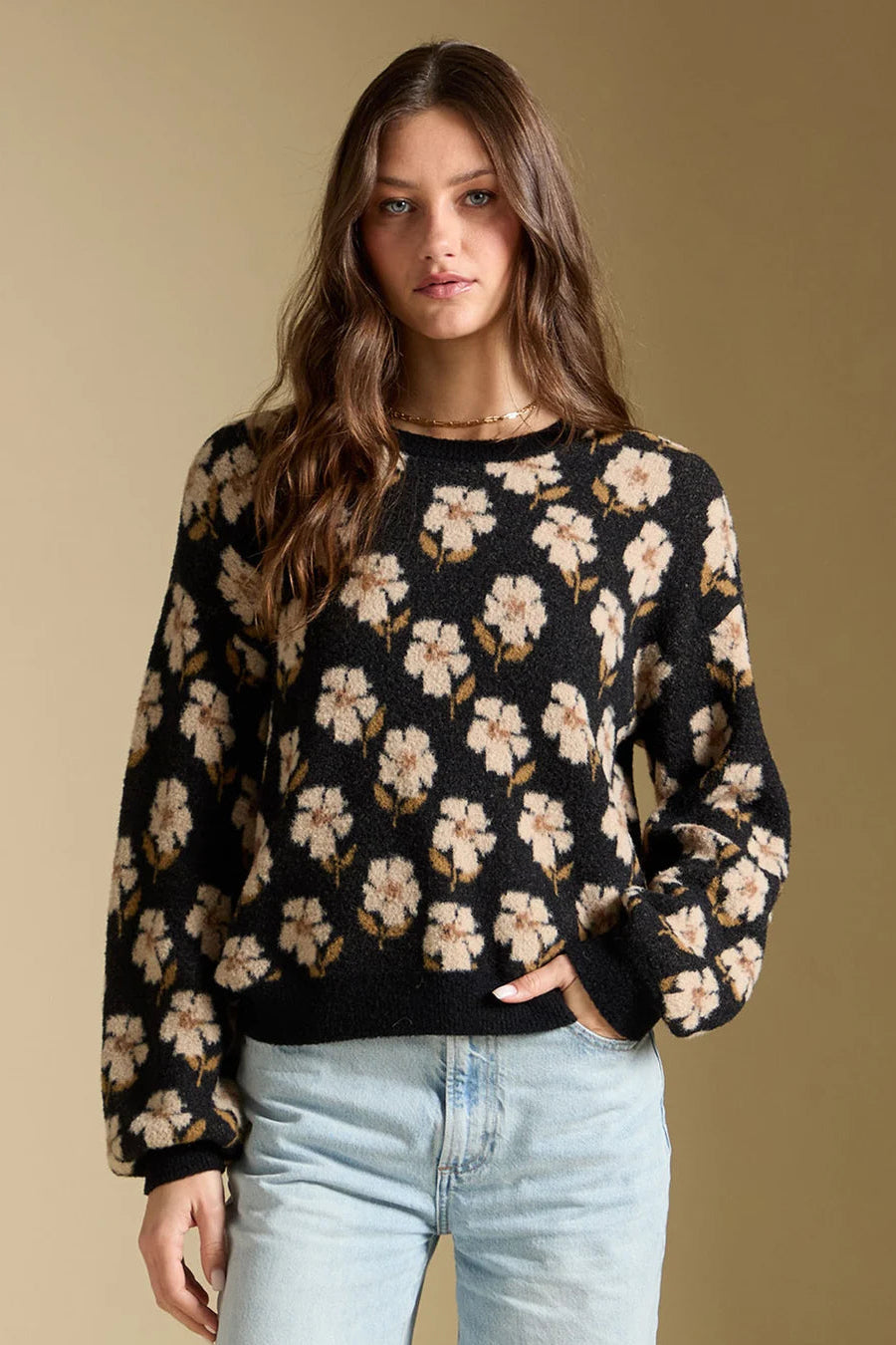 Woman wearing a black floral-patterned sweater against a beige background