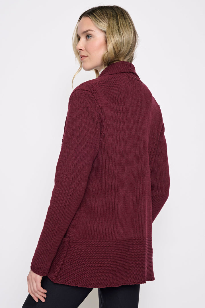 A woman wearing a maroon ribbed knit cardigan, shown from a side-back angle against a plain white studio background.