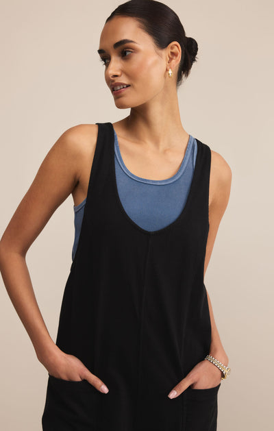 Woman wearing a black tank top with a blue interior panel against a beige background