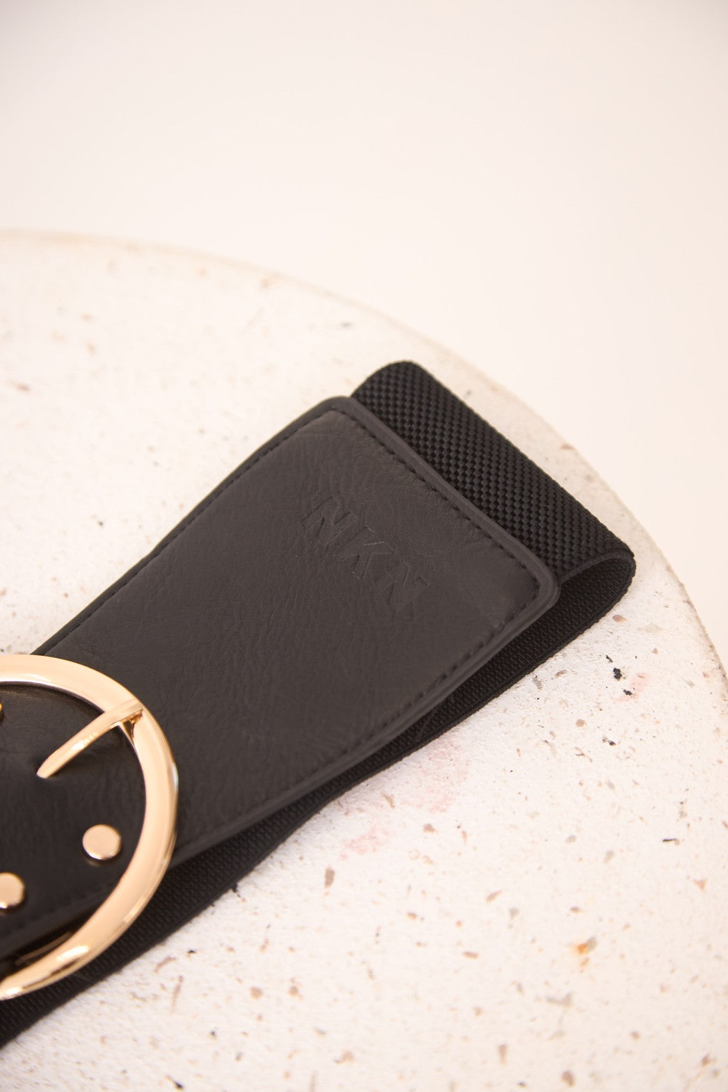 Black belt with a gold smiley face buckle on a light background