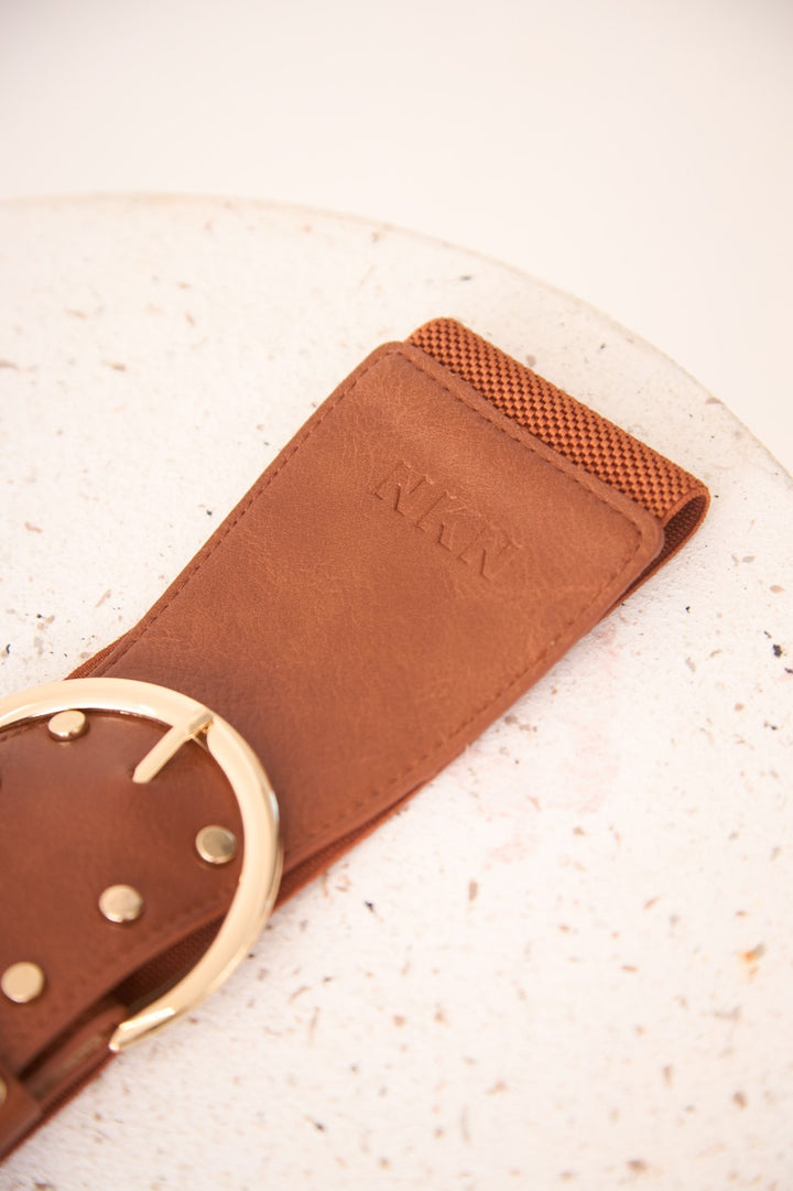 Brown leather belt with gold buckle on a textured surface