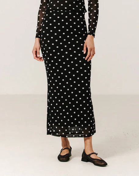 Woman wearing a black dress with white polka dots on a white background