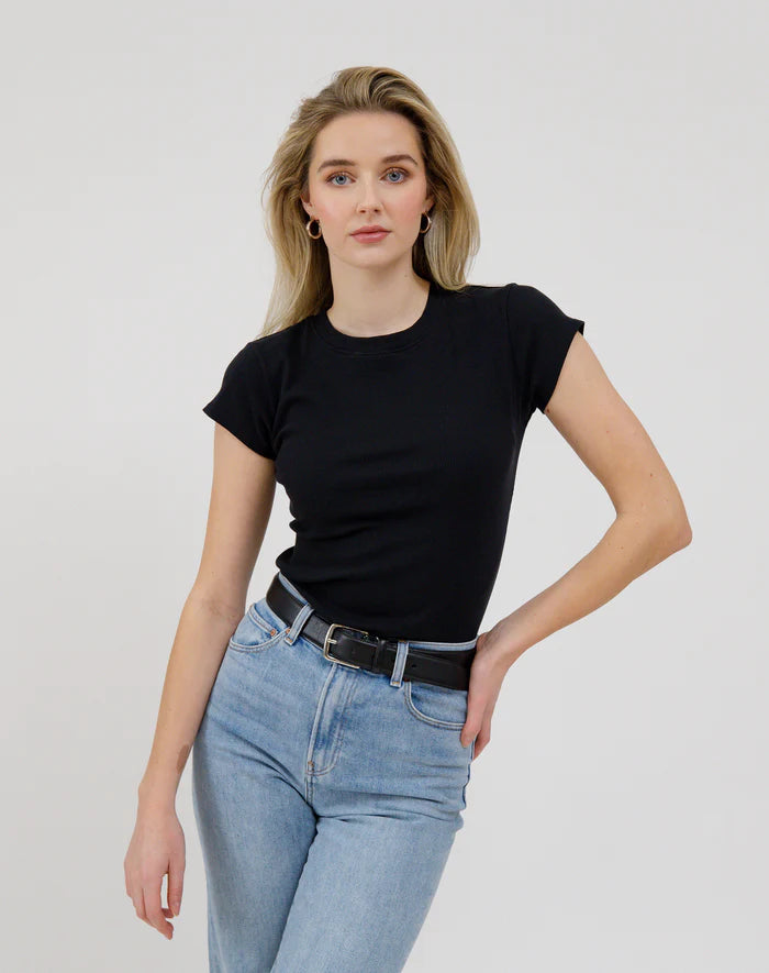 Woman wearing a black t-shirt and blue jeans against a plain background