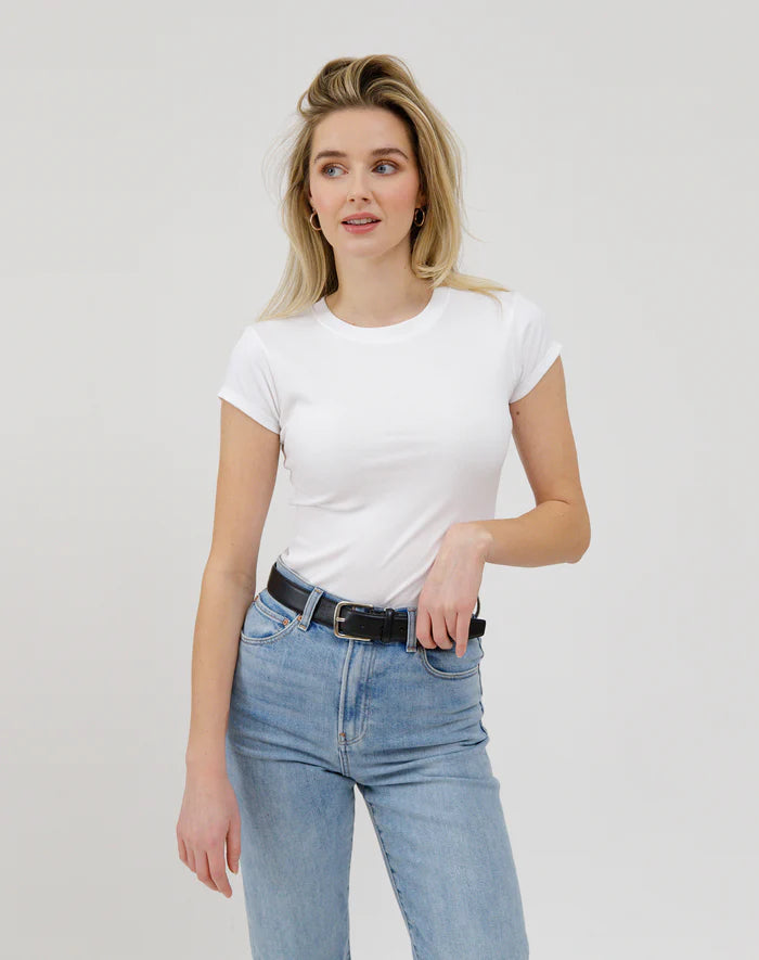 Woman wearing a white t-shirt and blue jeans against a plain background