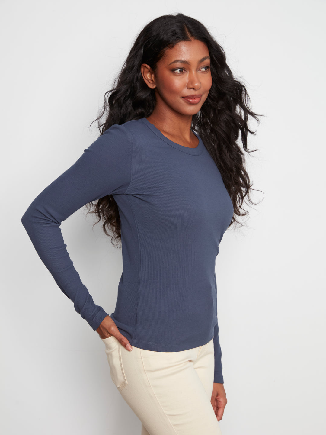 Woman wearing a blue long-sleeve top against a white background