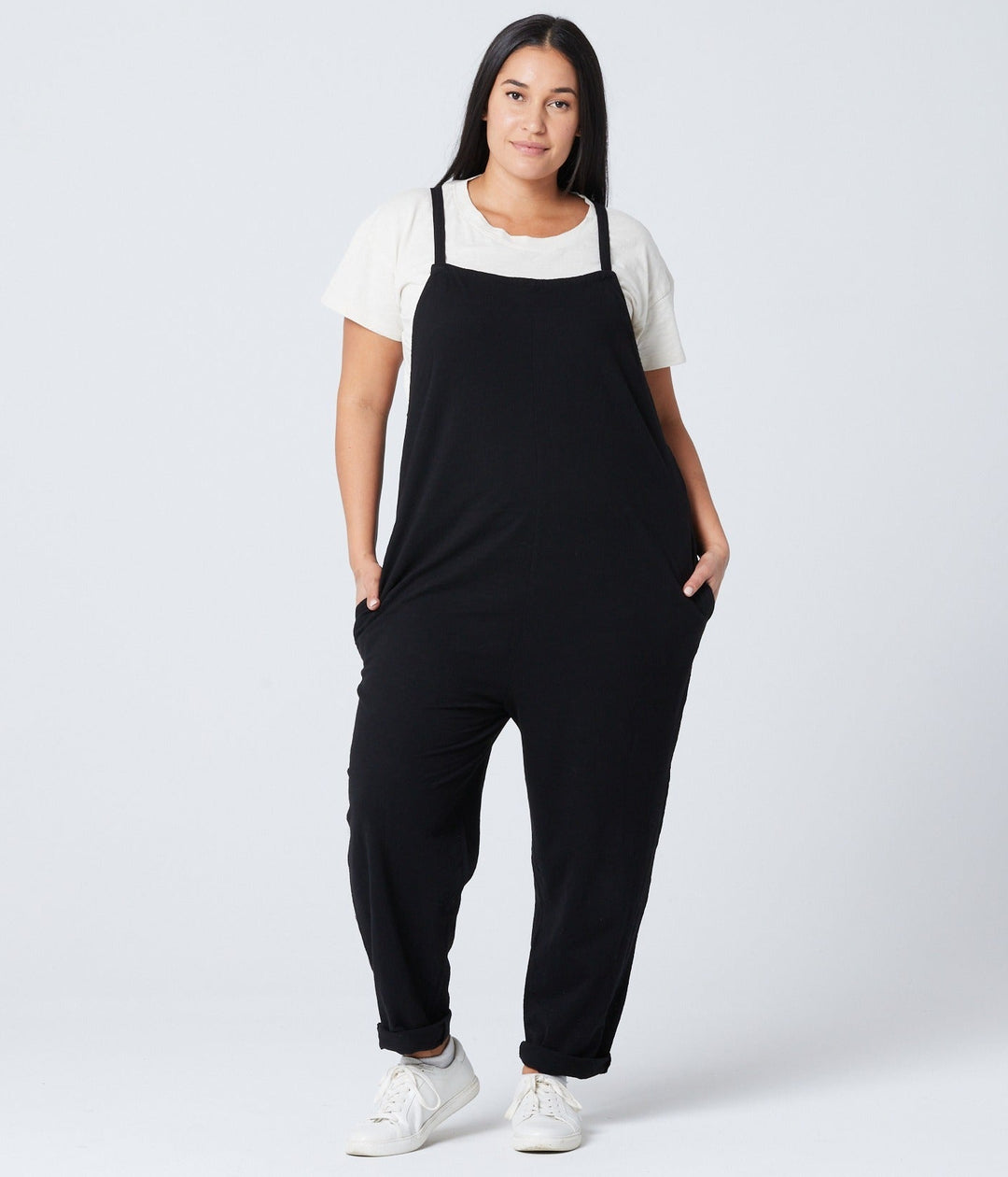 Person wearing a black overalls and white shirt on a white background