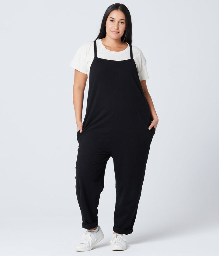 Person wearing a black overalls and white shirt on a white background