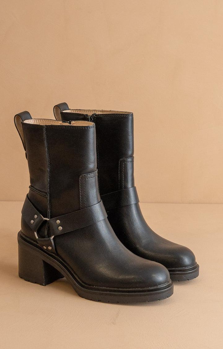 Black leather boots with block heels on a beige background