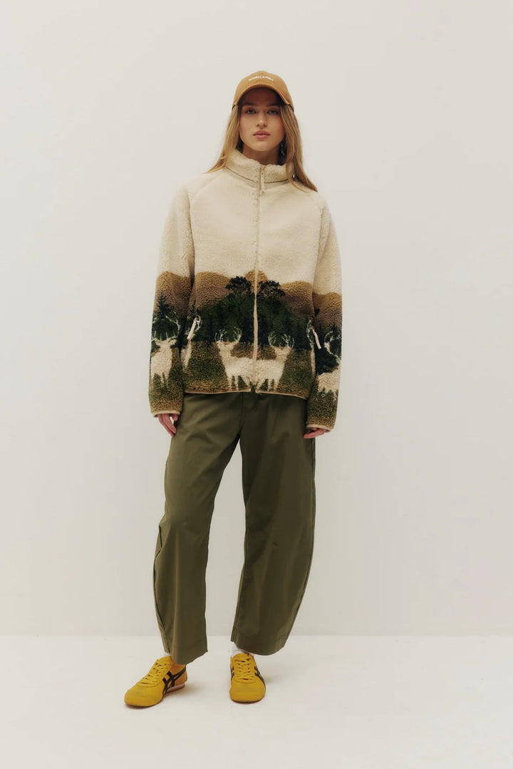 Person wearing a patterned sweater and green pants on a white background