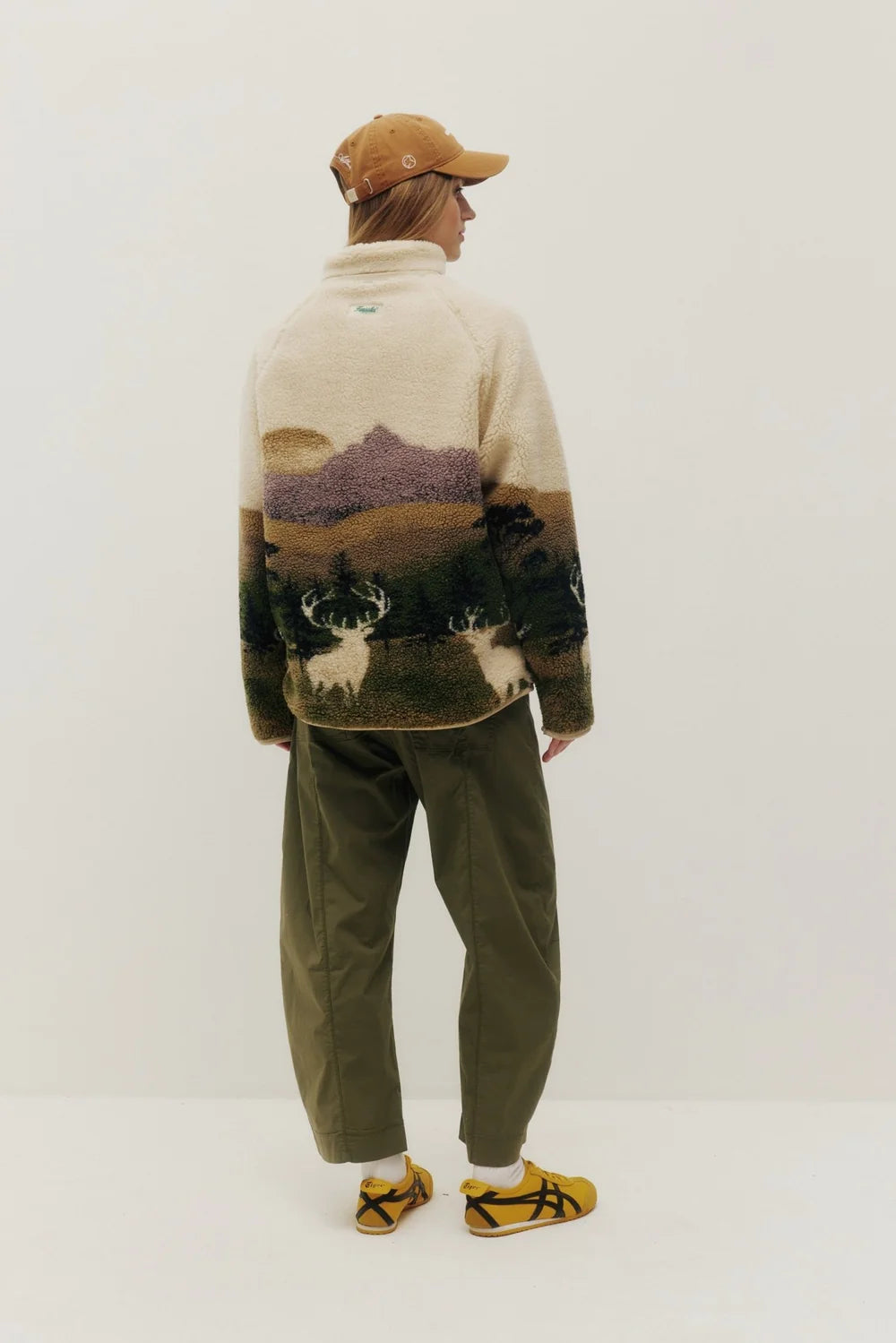 Person wearing a patterned sweater and pants on a white background