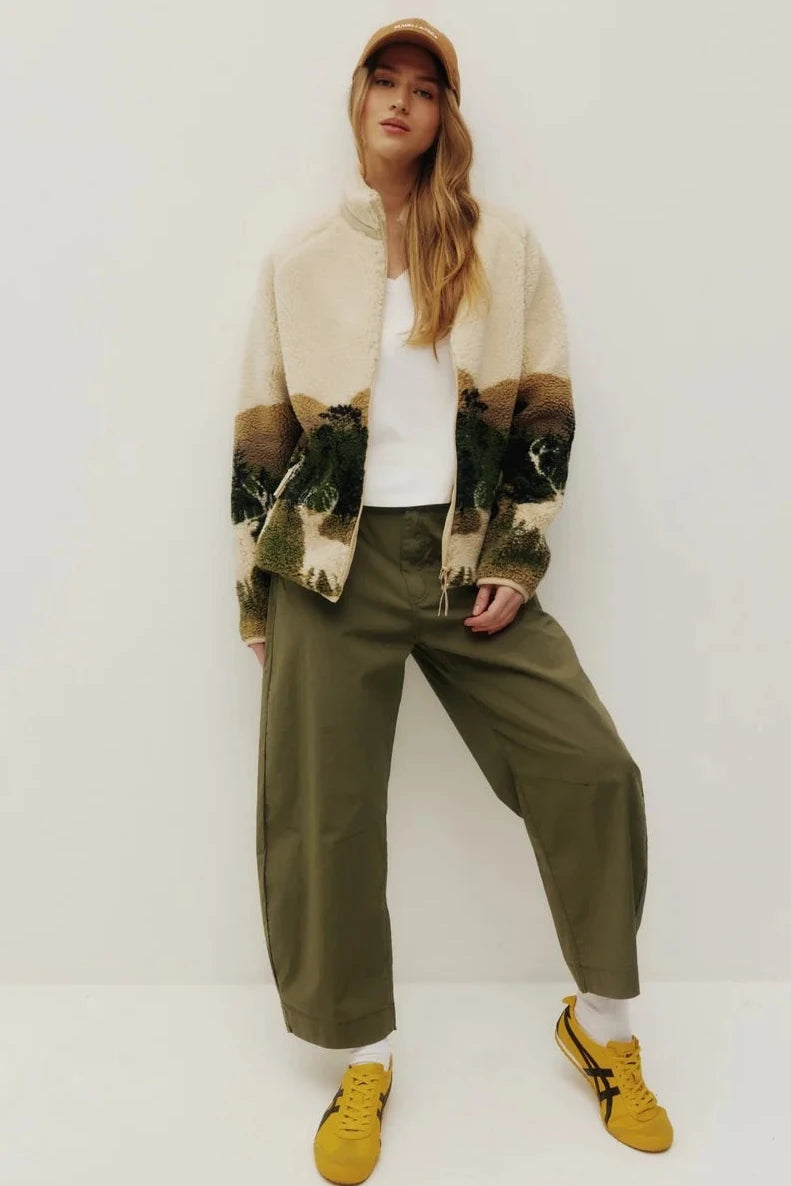 Person wearing a patterned jacket, white shirt, green pants, and yellow shoes on a white background