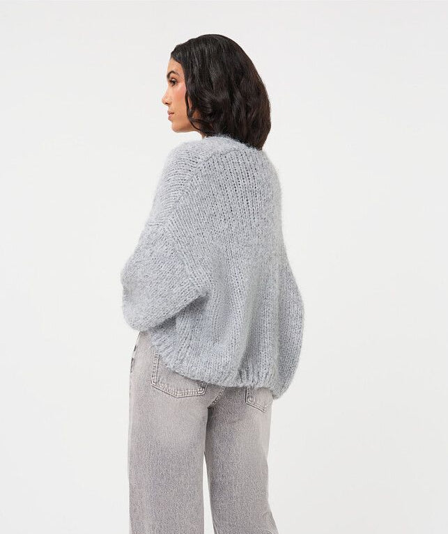 A woman shown from the back wearing a light gray fuzzy knit cardigan and matching wide-leg gray jeans against a plain white studio background.